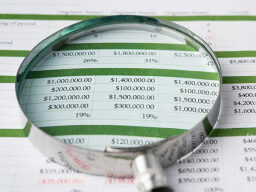 a magnifying glass sitting atop a budget spreadsheet