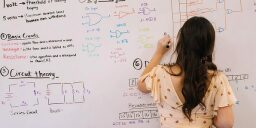 a woman writing math problems on a whiteboard