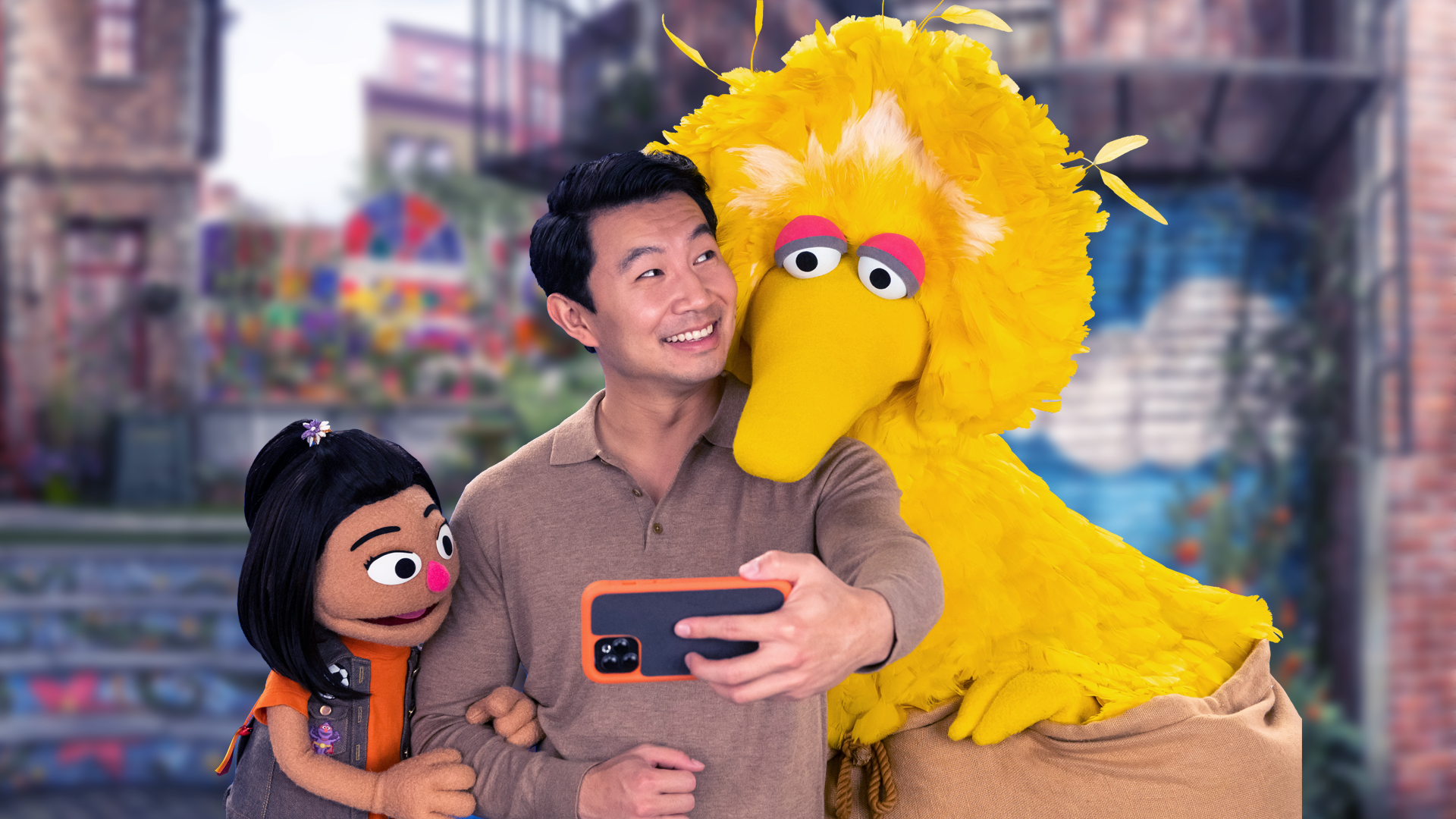 Actor Simu Liu, muppet Ji-Young, and Big Bird take a selfie on Sesame Street.