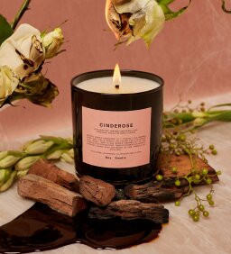 lit candle surrounded by flowers and burnt pieces of wood