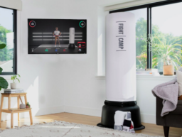 white fightcamp punching bag next to TV with fightcamp app onscreen