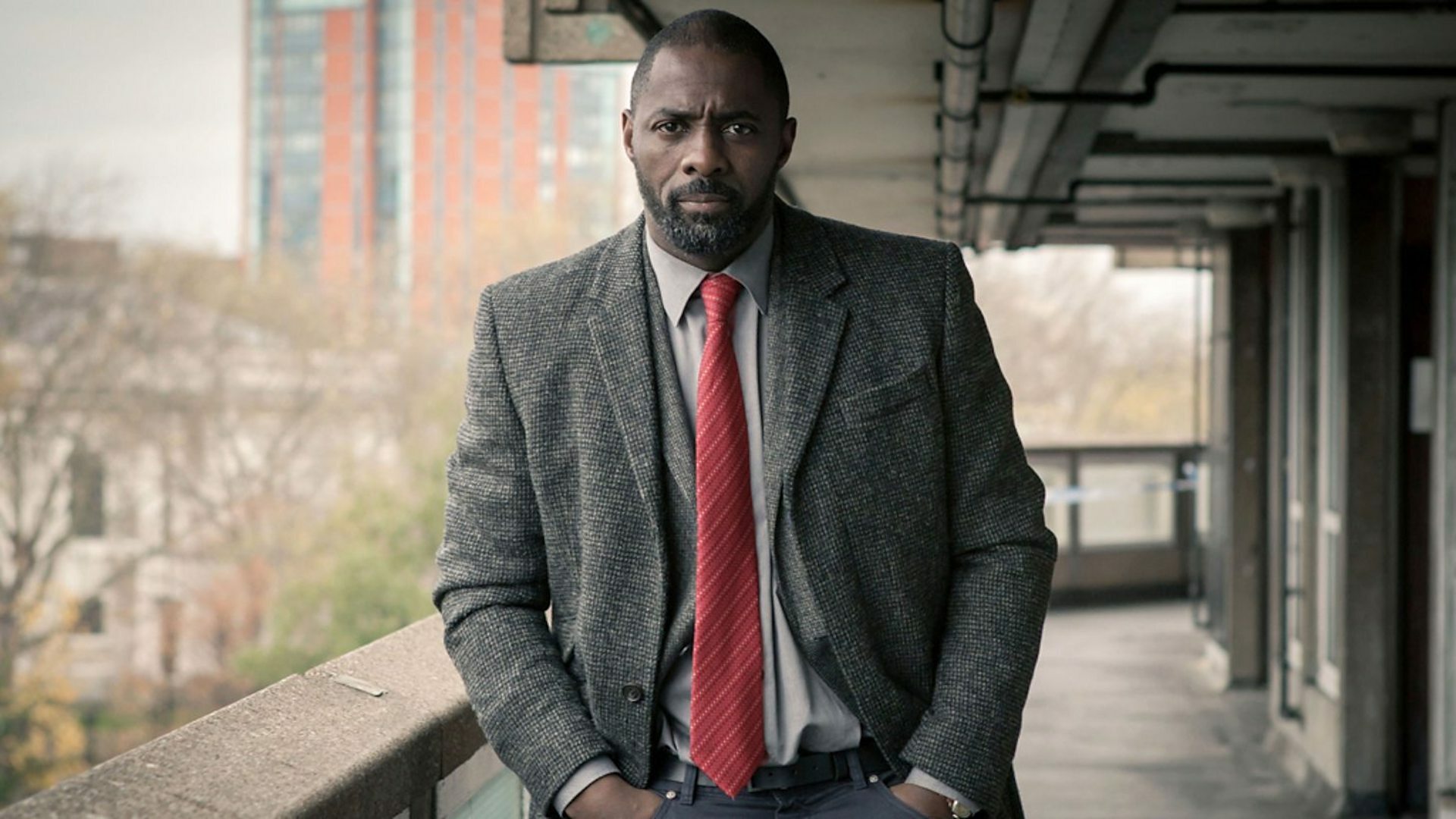 An image of Idris Elba in "Luther" standing on an apartment balcony. 