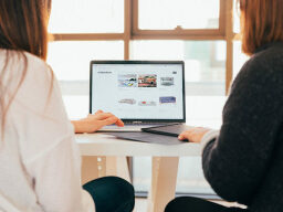 Two people sitting in front of a laptop open on a shopping website