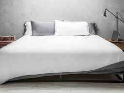 Bed with white sheets and gray and white pillows