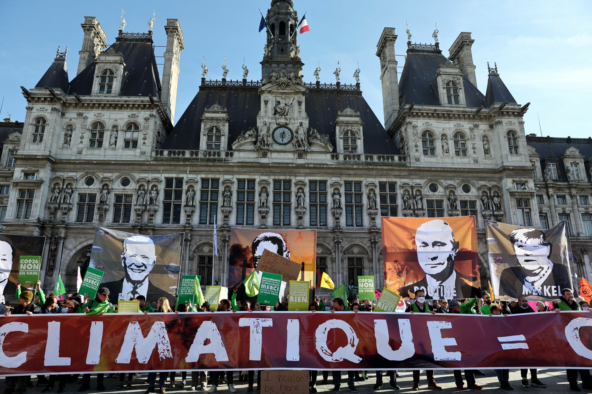 Protesters hold portraits of world leaders and a banner reading "Climate inaction = crimes against the living" as they demonstrate in Paris.