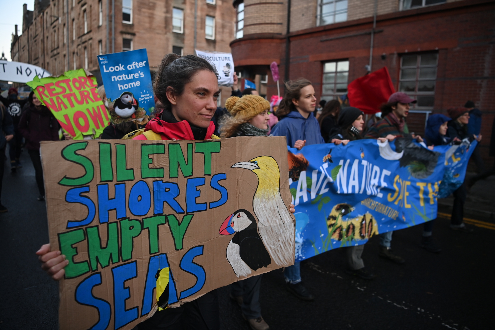 Climate protesters carry a placard saying "Silent Shores Empty Seas" in Glasgow.