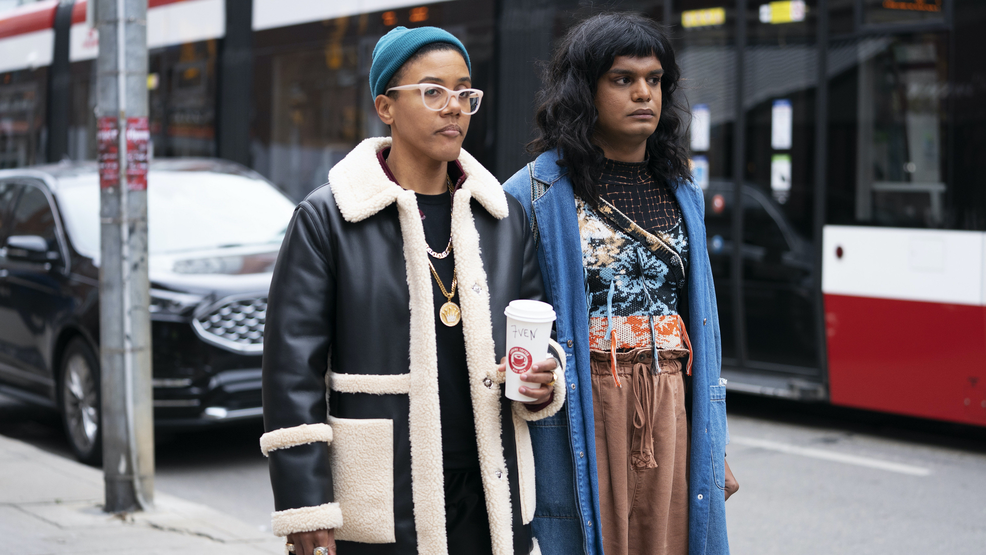 Two friends stand on a sidewalk looking lost.