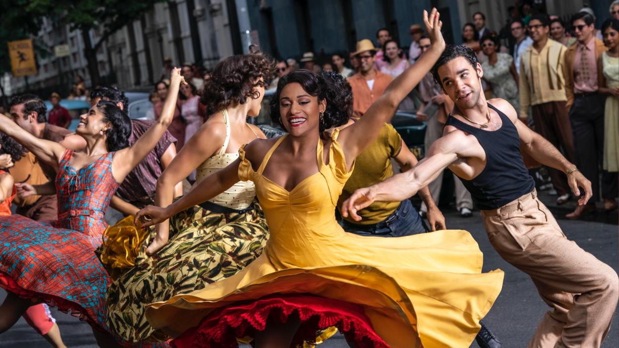Men and women in vibrant clothes dance in the street