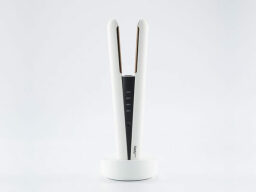 White straightening iron standing upright in stand