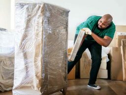 Person in green clutter shirt wrapping furniture