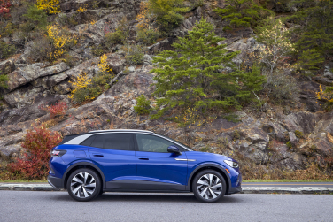 A blue car drives on a road next to the freeway.