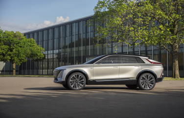 Car in front of glass buildings and trees.
