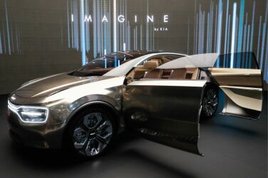 The word "Imagine" behind a gold car with doors open