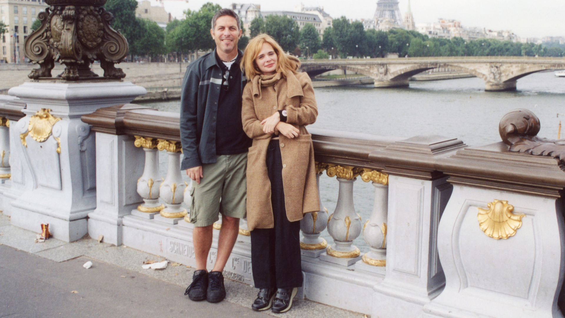 Andy Ostroy and Adrienne Shelly on a bridge in Paris, his arm around her shoulders.