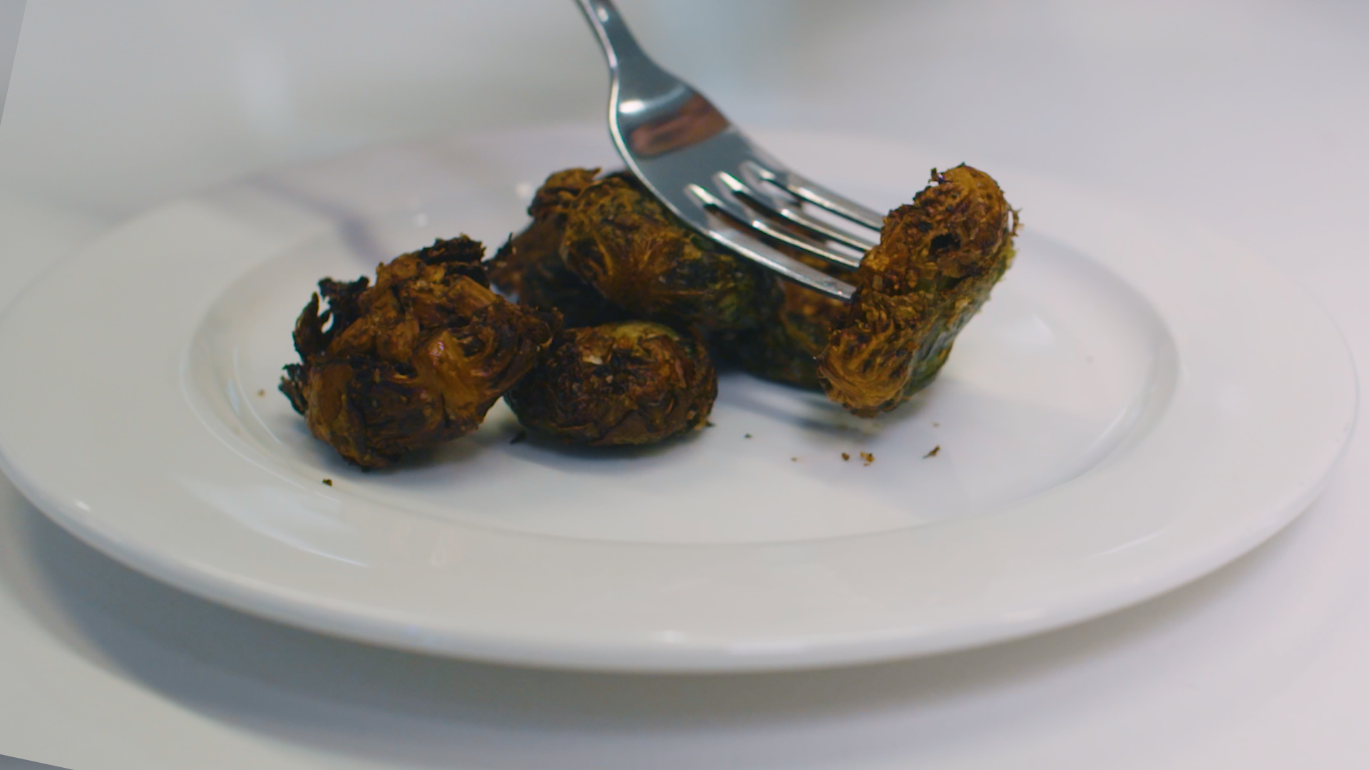 crispy brussels sprouts on plate, one picked up by fork