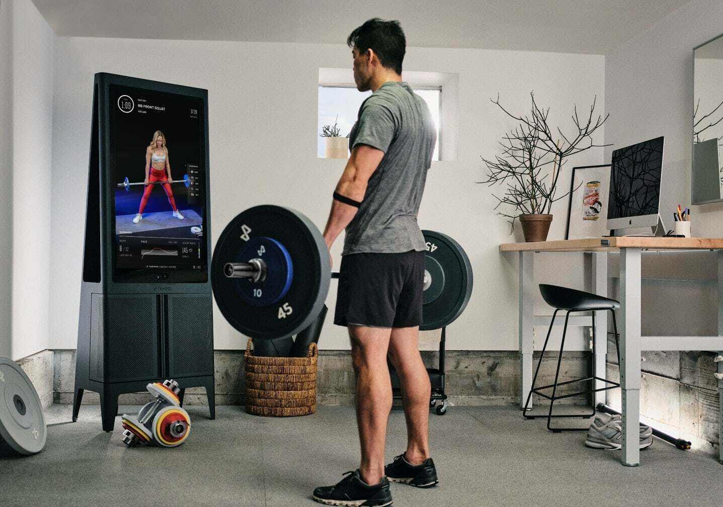 Man lifting weights, following along with a trainer on the screen