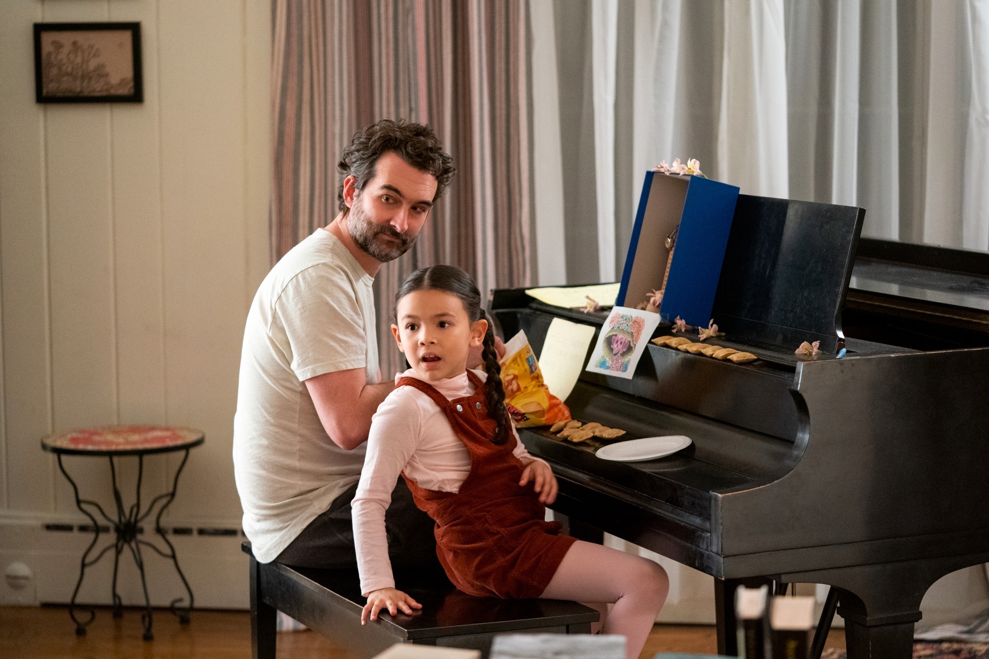 A man and a child sit at a piano.