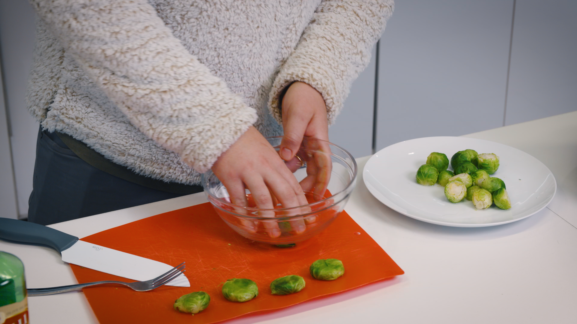 person smashing down brussels sprouts with bottom of bowl