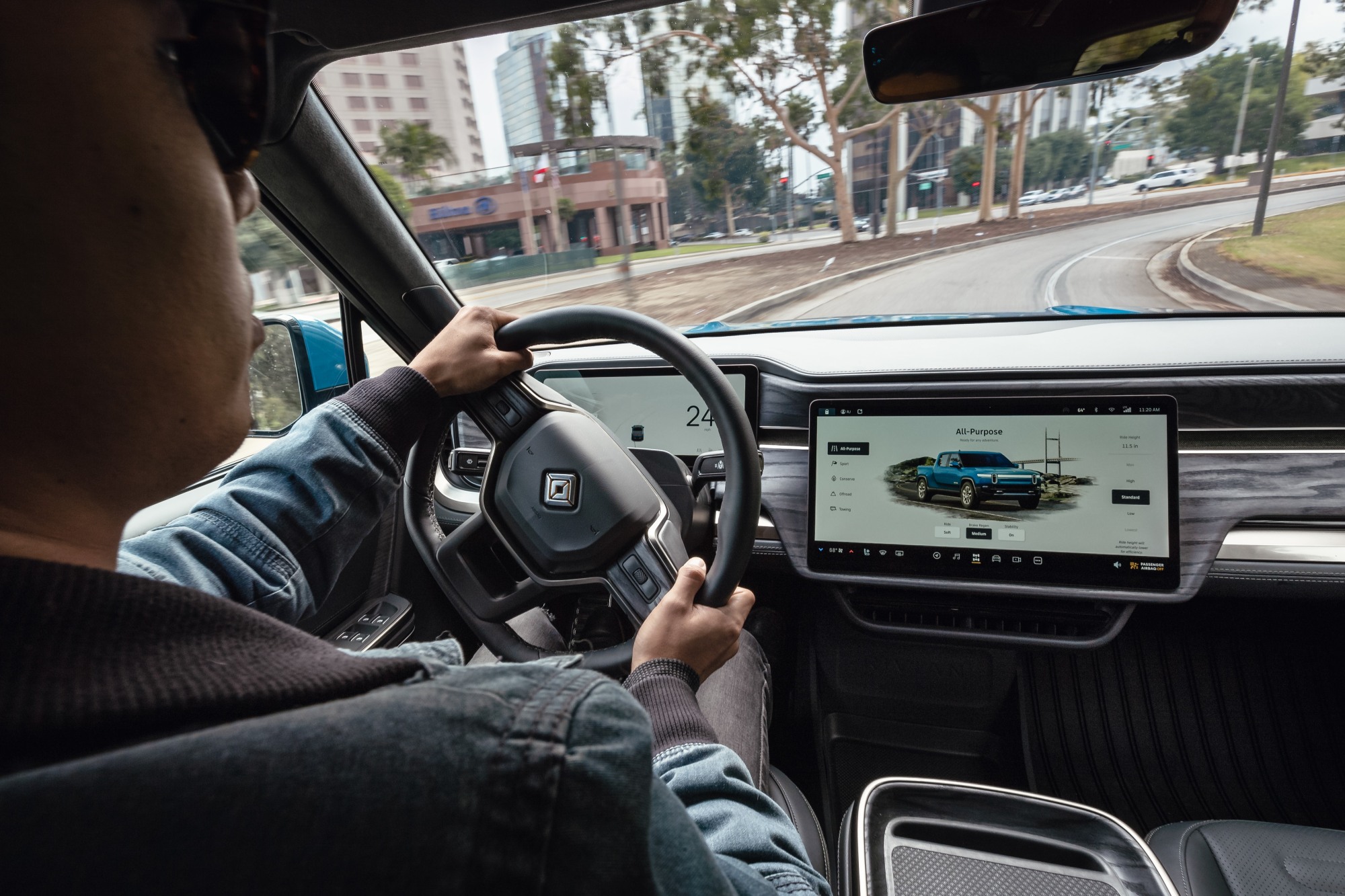 Over-the-shoulder view of the Rivian R1T steering wheel and touchscreen.