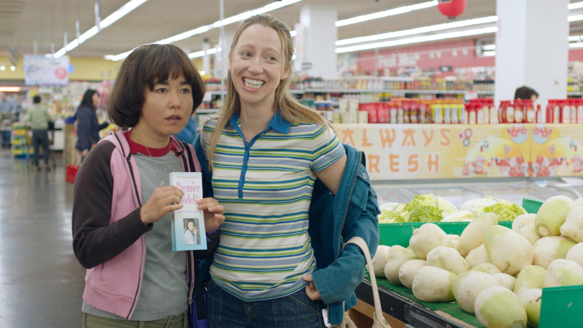 Two girls stand in a grocery store with a pamphlet