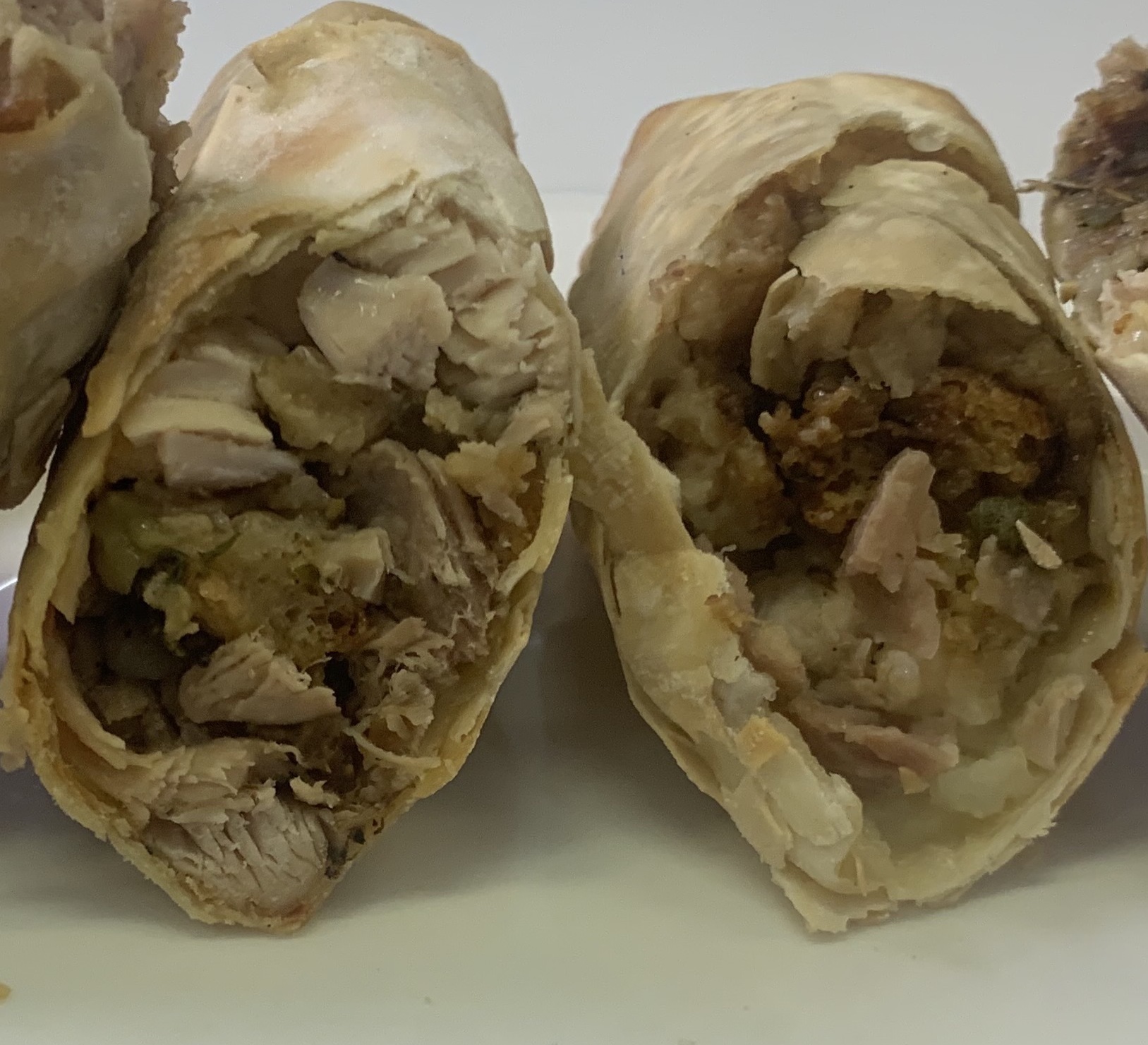 cooked egg rolls cut in half showing Thanksgiving leftovers inside