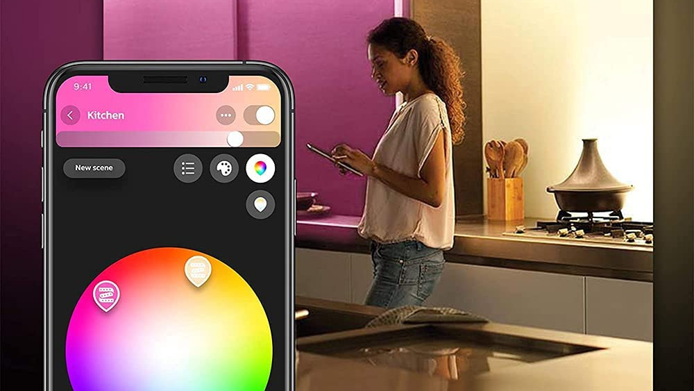 Image of woman standing kitchen controlling ambient lighting from her phone.