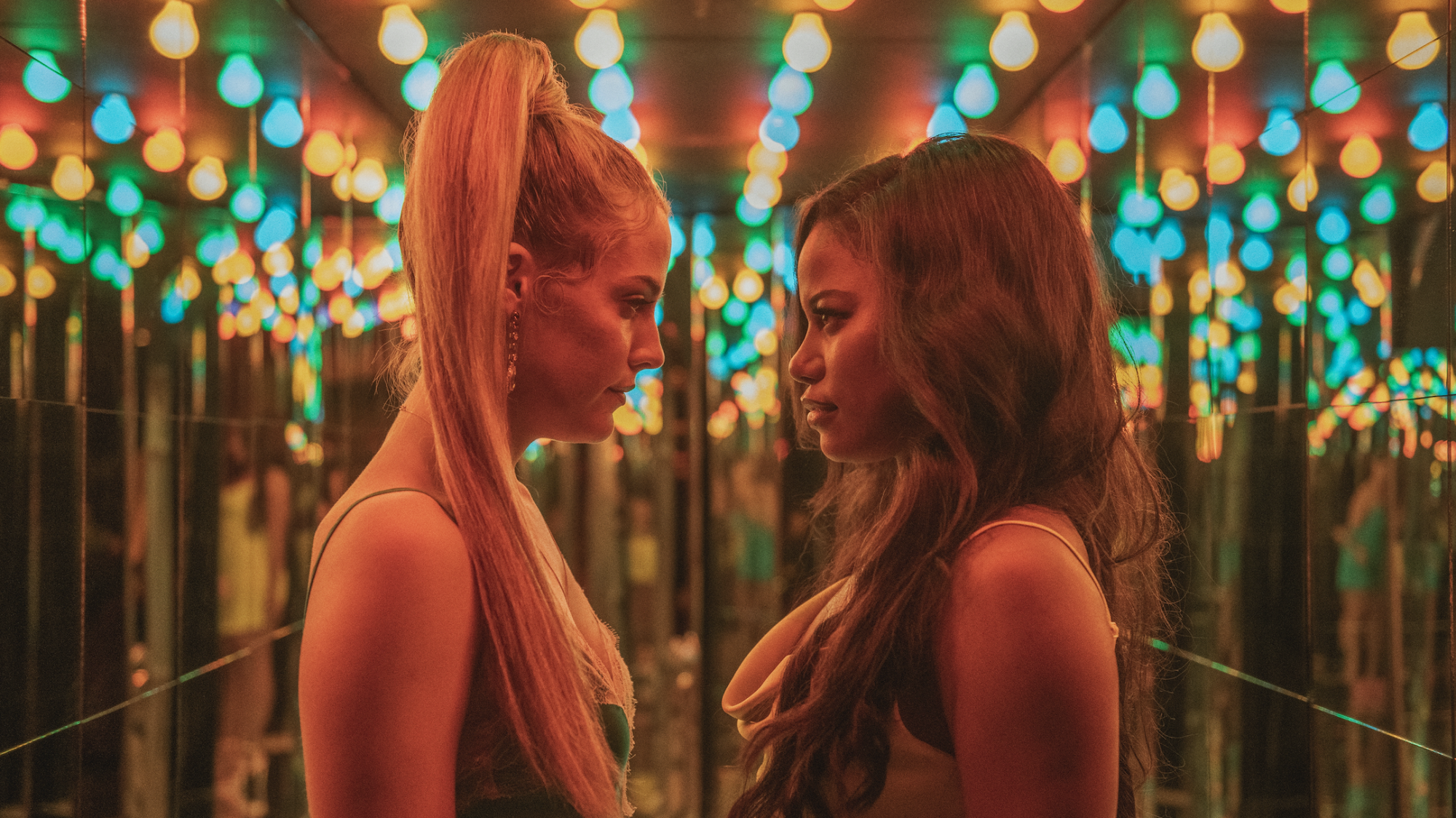 Two women face each other in a room of mirrors.