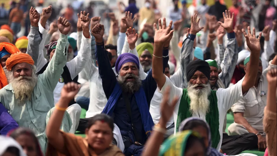 A large crowd of people protest with their hands raised.