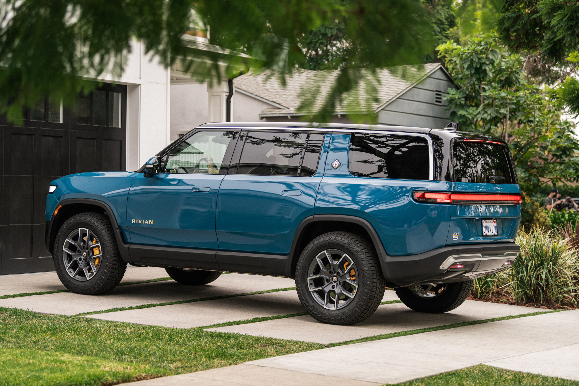 A blue SUV sits in a driveway in front of a garage.