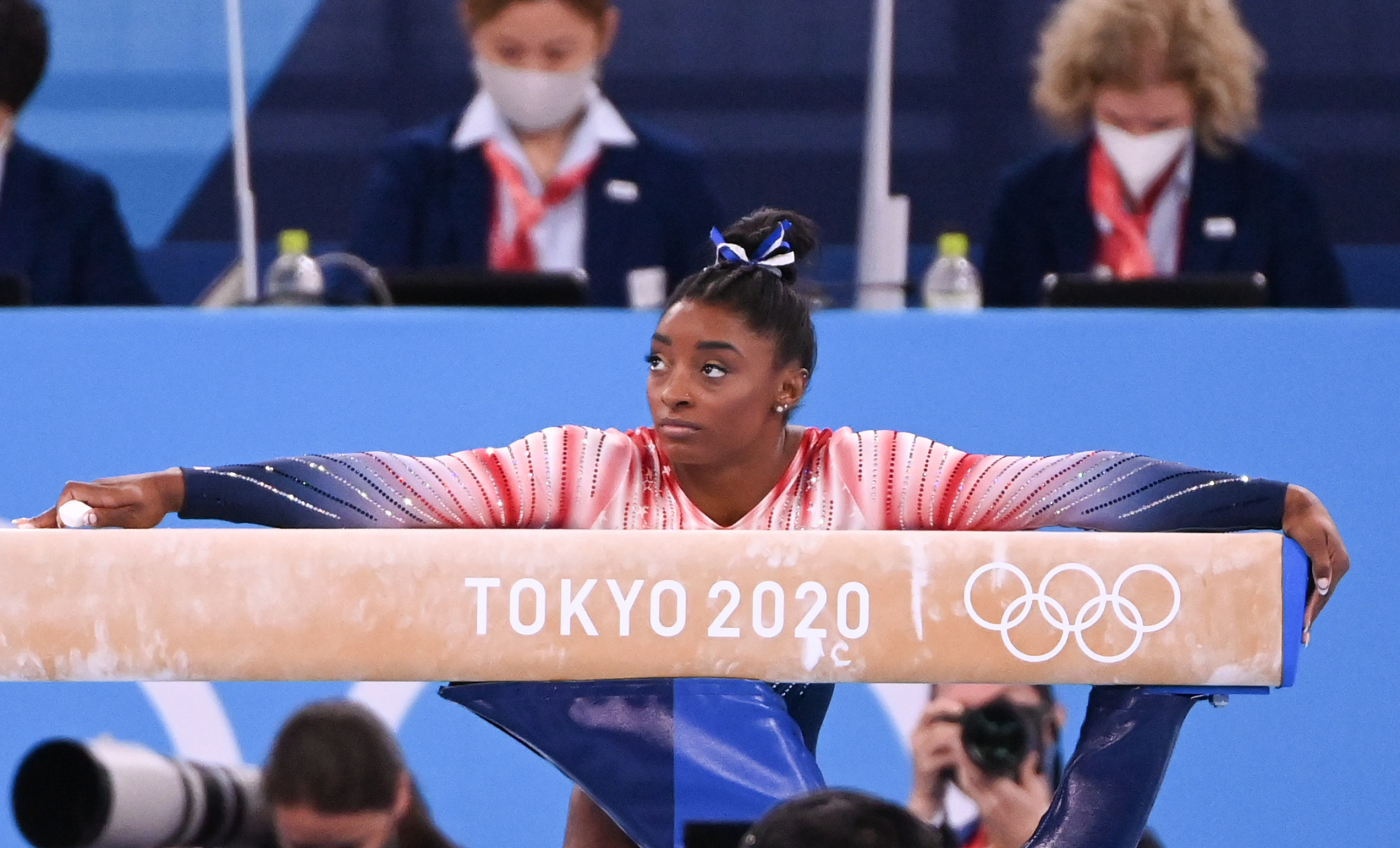 Simone Biles leans on a balance beam during the Tokyo Olympics.