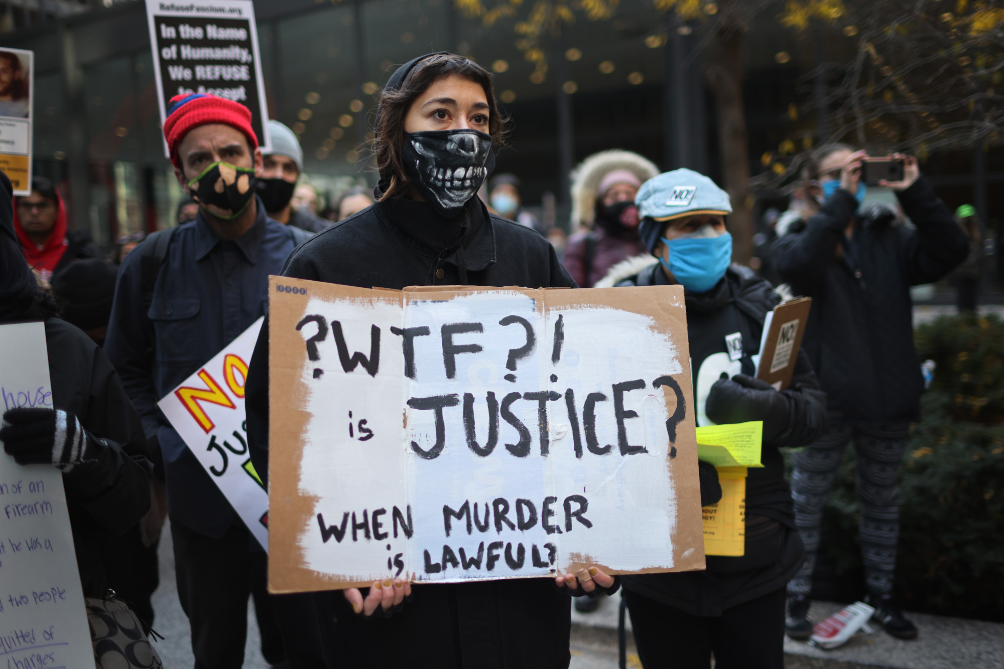 A protester holds a sign that reads, "Wtf is justice when murder is lawful?"