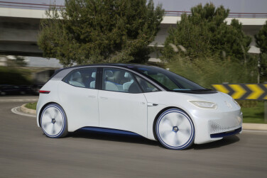 A white car with tinted blue windows goes by a road sign.
