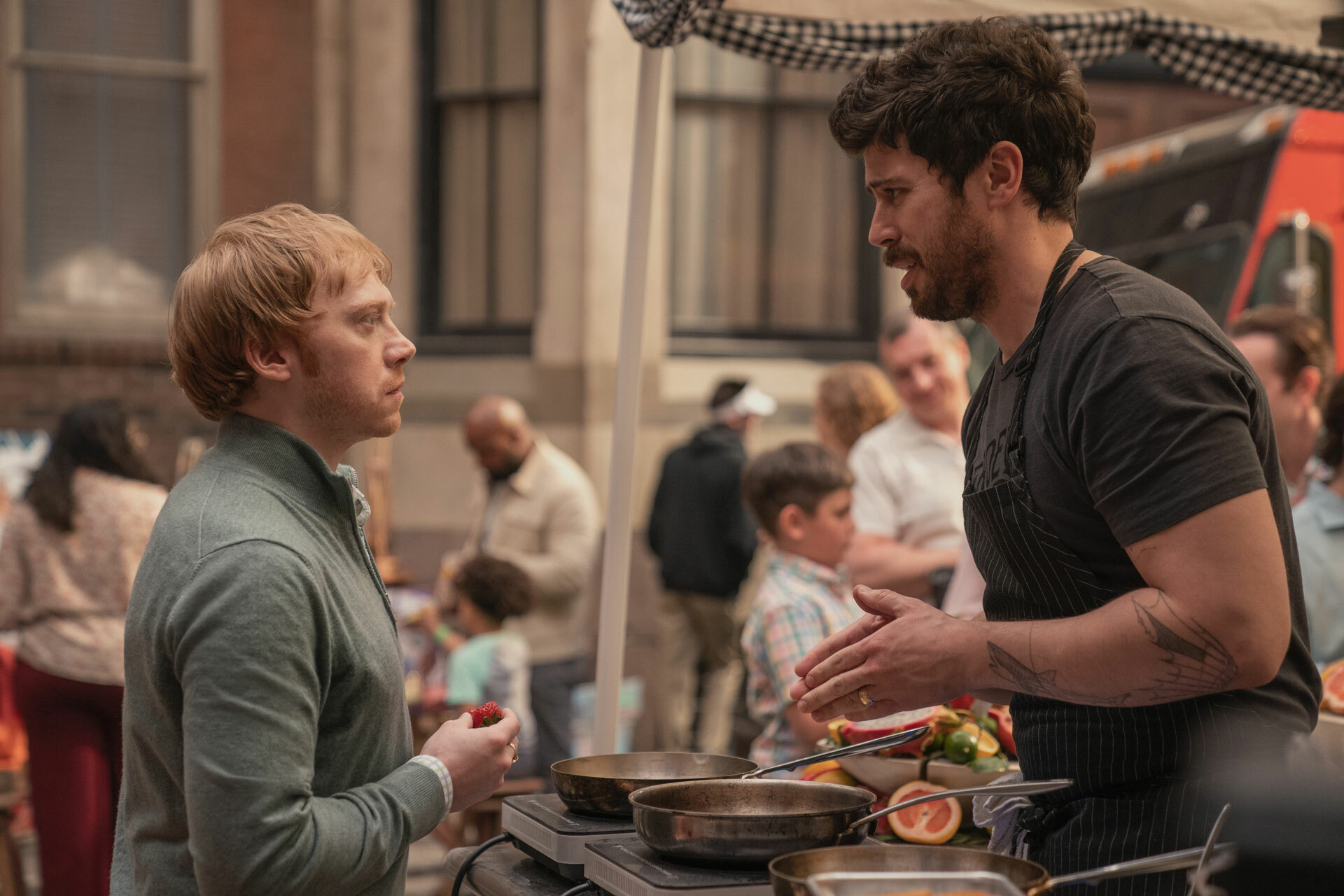 A still from the Apple TV+ series, Servant. Two men stand facing each on a crowded city street.