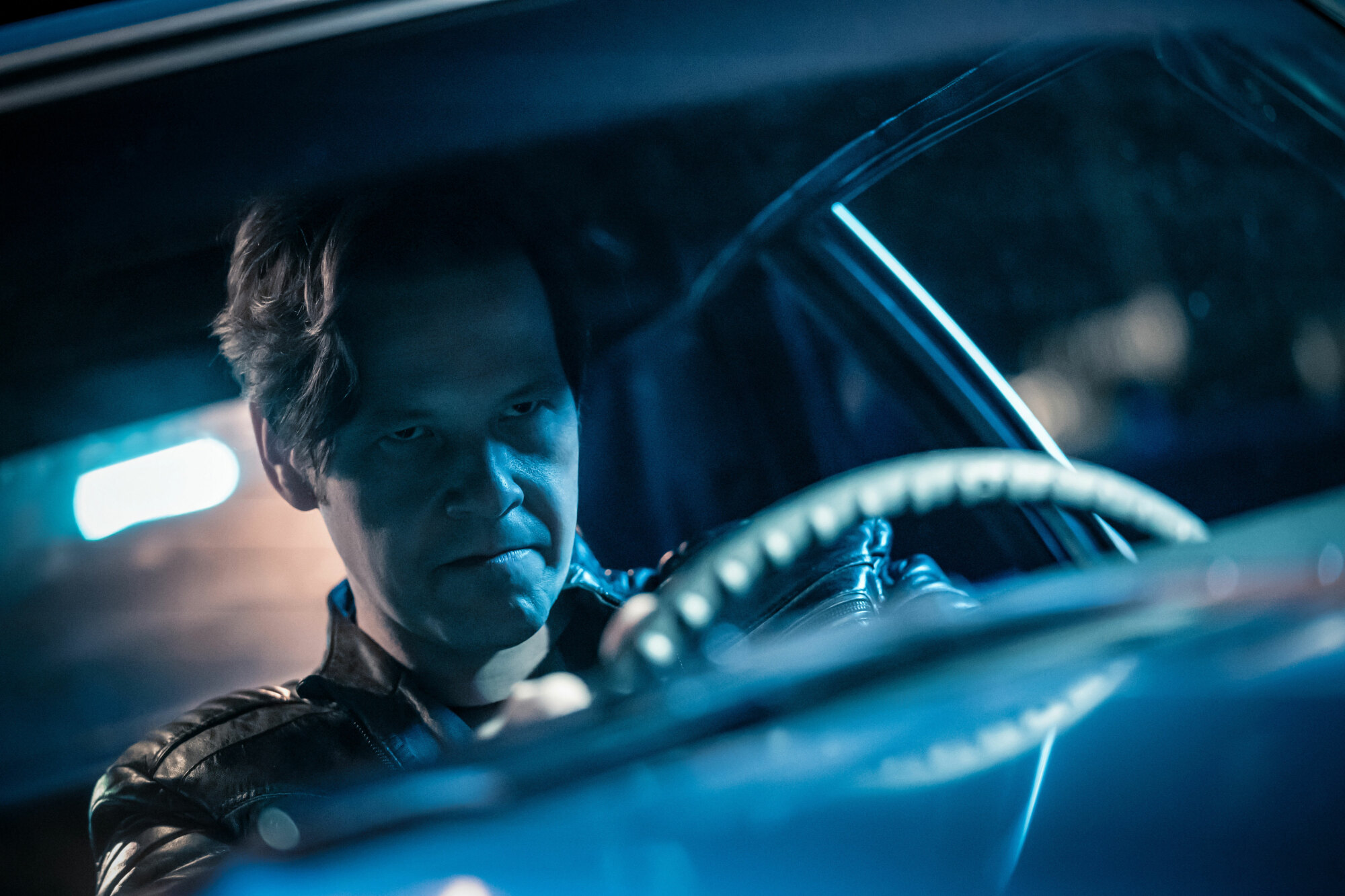 A still from "The Afterparty" on Apple TV+. A close-up of a man's face as he sits behind the wheel of a car staring intently, almost angrily, at whatever's in front of him outside.