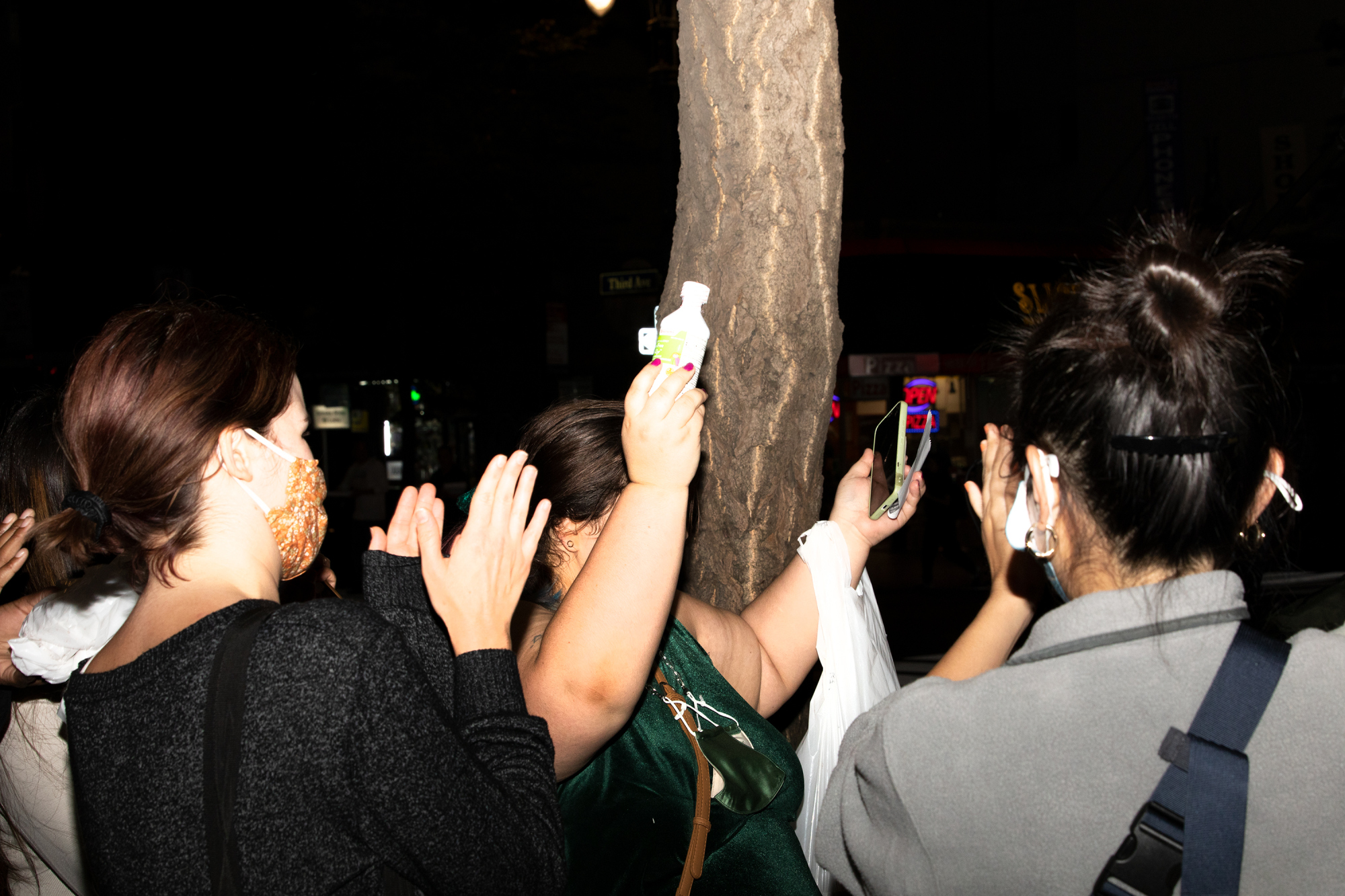 Individual holding up medicine bottle surrounded by crowd who is clapping