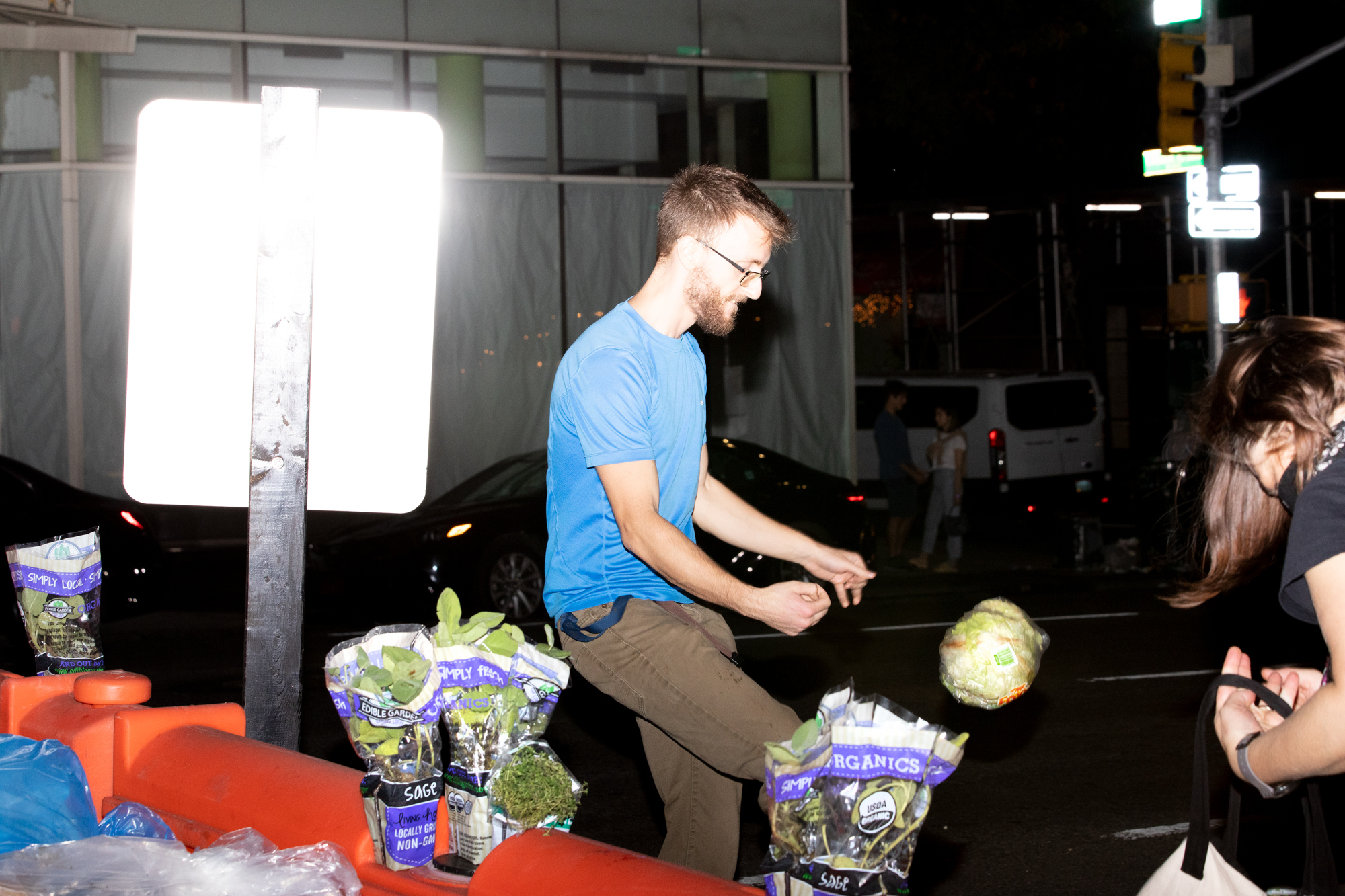 individual kicking up head of lettuce next to street sign