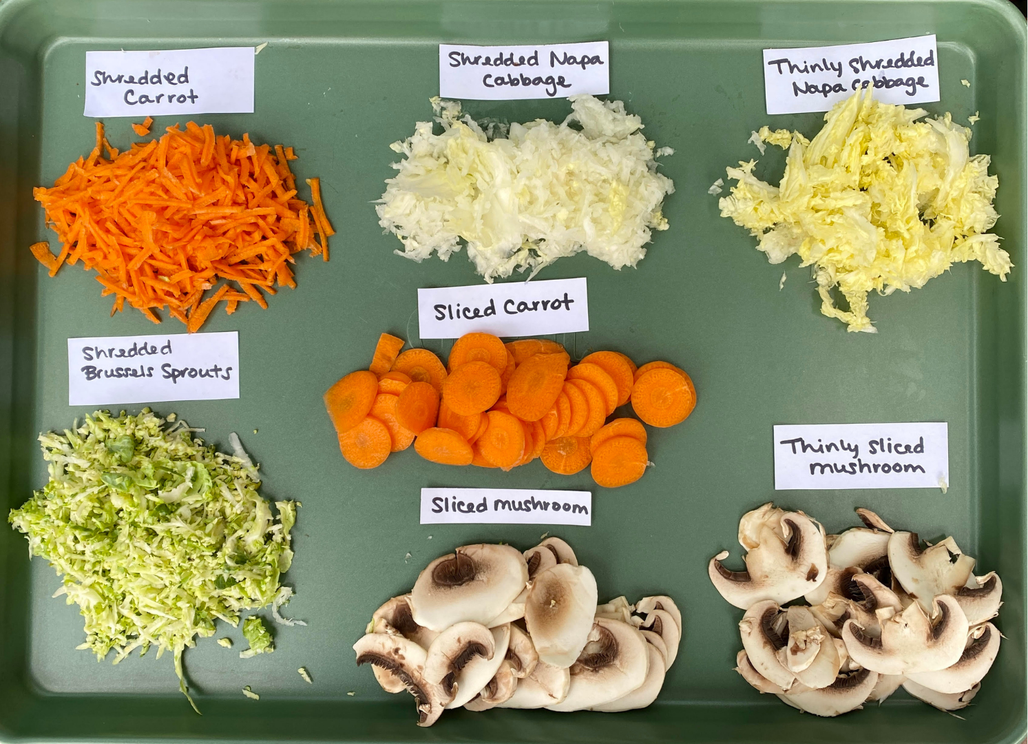 From left to right: Shredded carrot, shredded Napa cabbage, thinly shredded Napa cabbage, sliced carrots, shredded Brussels sprouts, sliced mushrooms, and thinly sliced mushrooms.