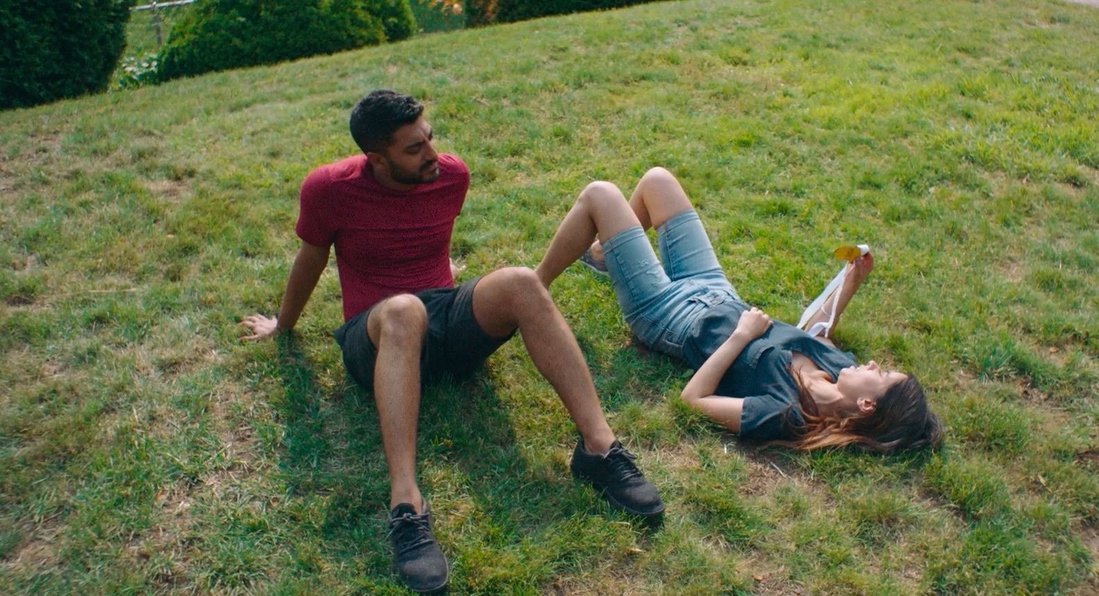 An adult brother and sister lay in the grass - a still from "Definition Please."