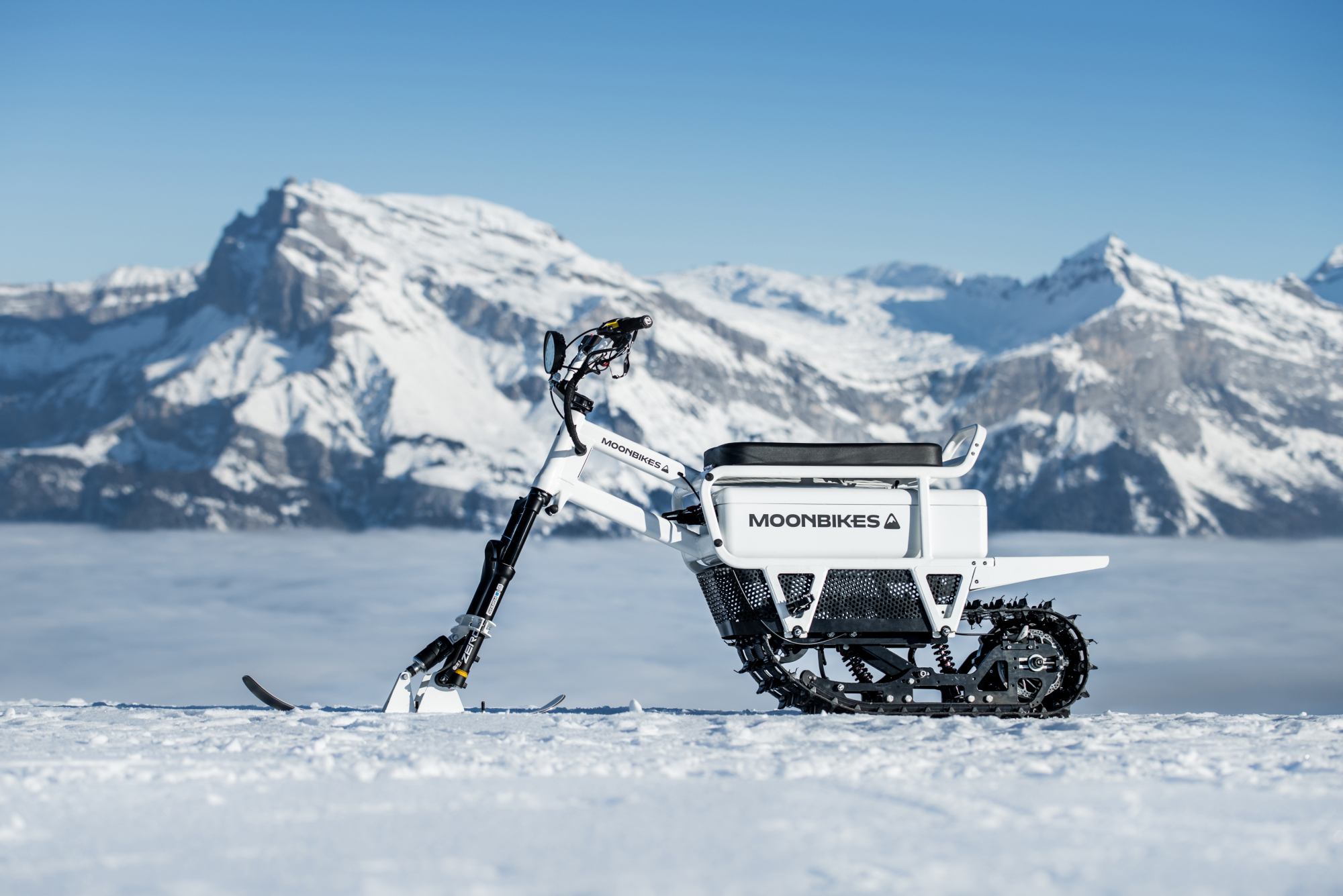 A bike stands on snow with a snowy mountain in the background