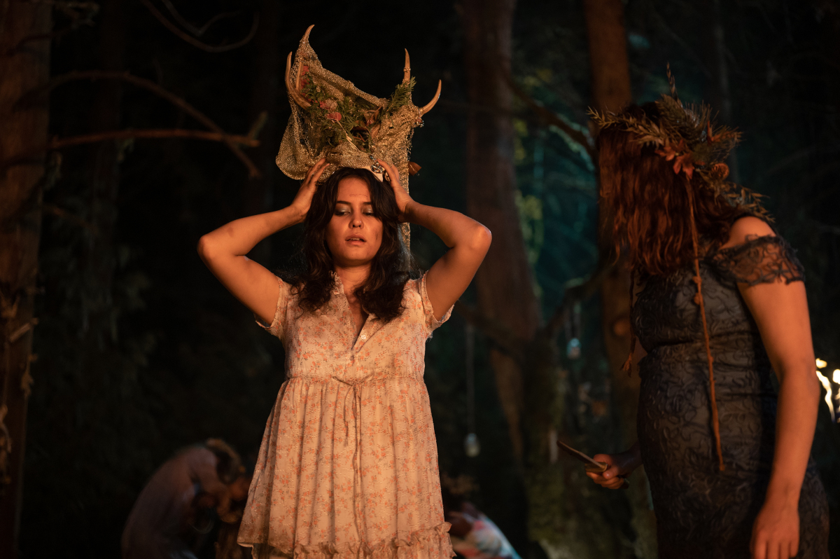 A young woman in a white dress wearing a head dress of antlers.