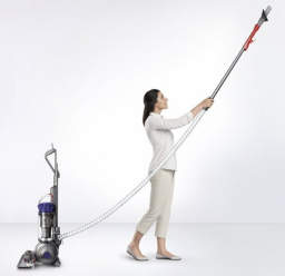 person hoisting the attachment of a dyson vacuum into the air to reach a high place