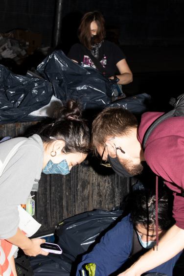 Two individuals searching through trash bags