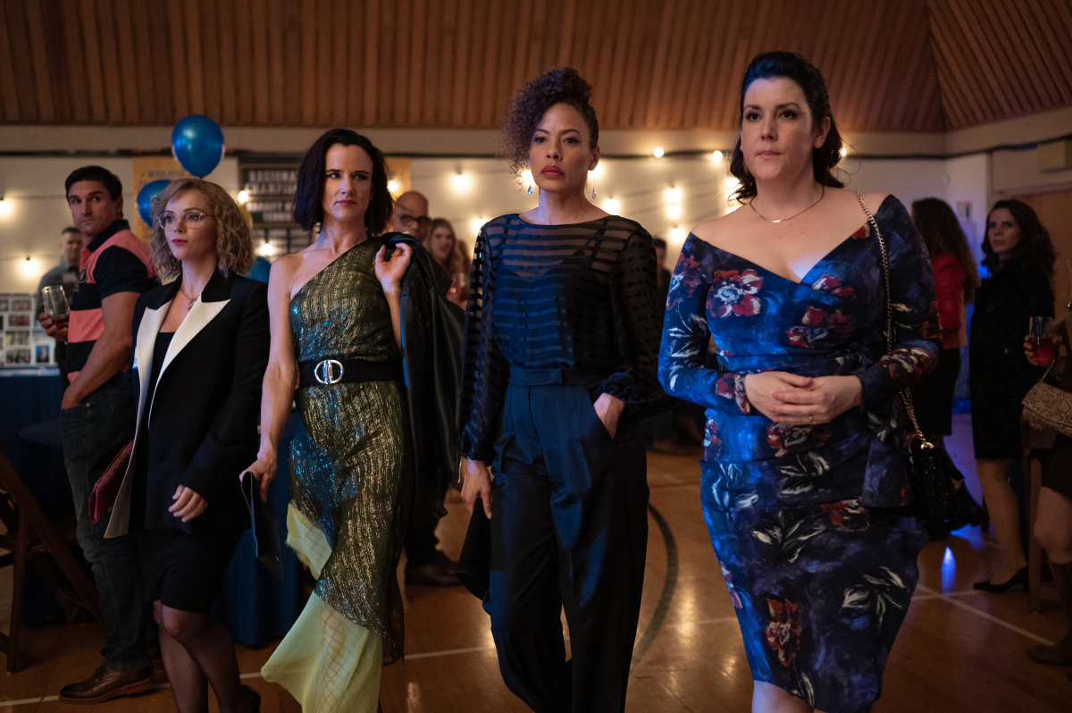 The 'Yellowjackets' adult main cast in a scene from the Season 1 finale, wearing smart outfits at an event..