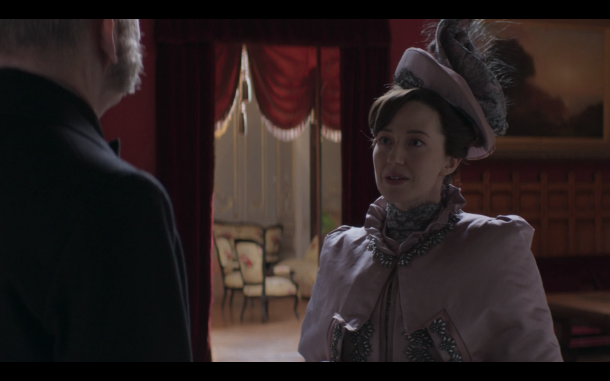 A woman in a purple sink cape standing in an opulent 19th century brownstone foyer.