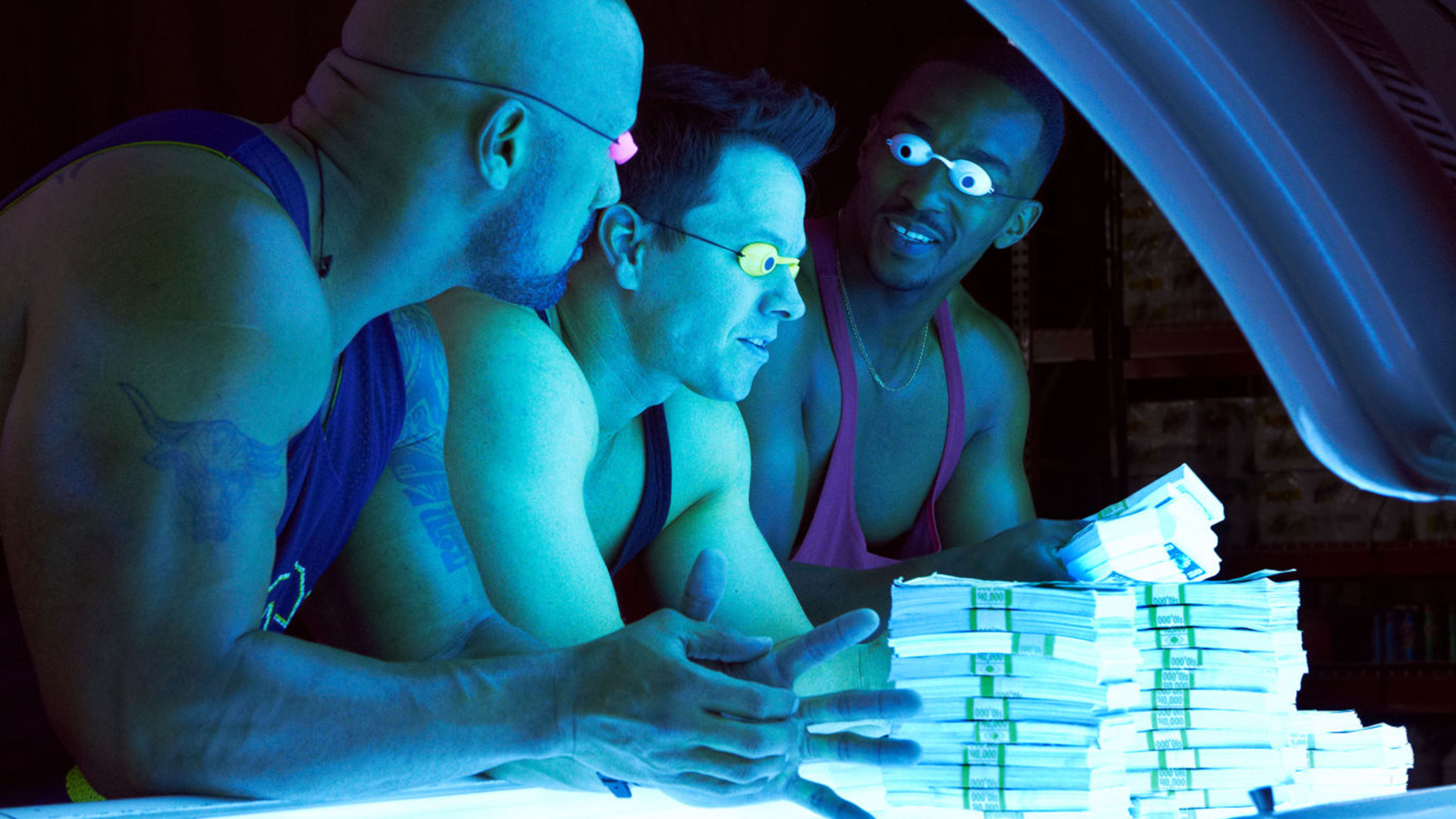 Three burly men lean into a sun bed, where a pile of money is stacked high. 