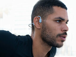 Person wearing grey earphones hooked over ear 