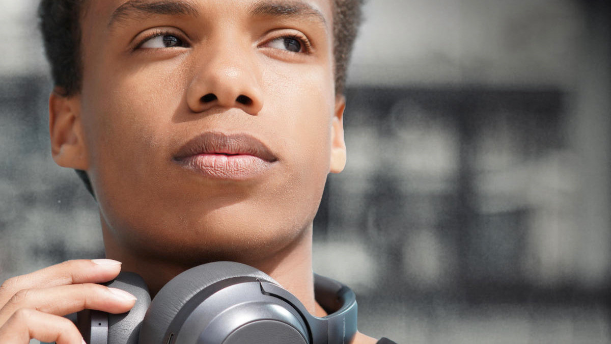 Person looking to the side wearing black headphones around neck