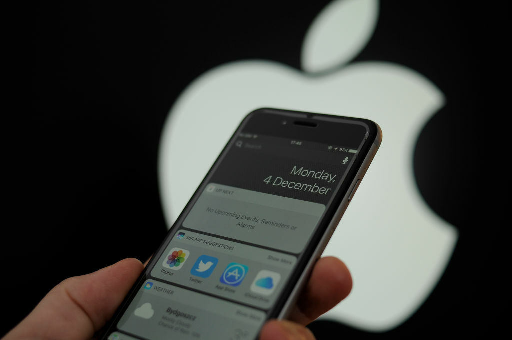 An iPhone held in front of the Apple logo.