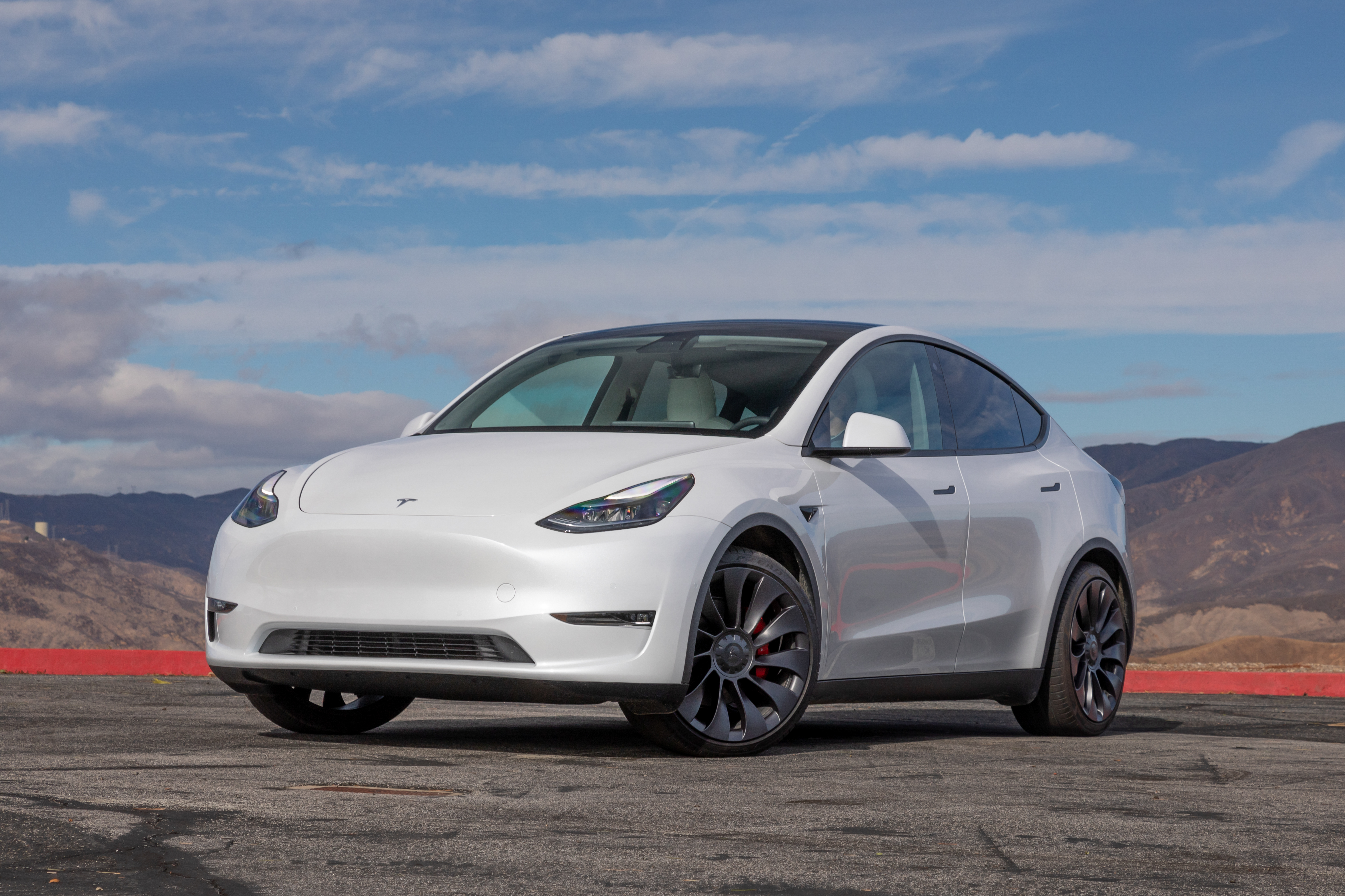 A white Tesla Model Y with a mountainous background.