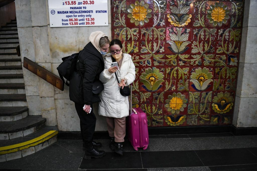 Two people look at a smartphone near a Kyiv metro station.